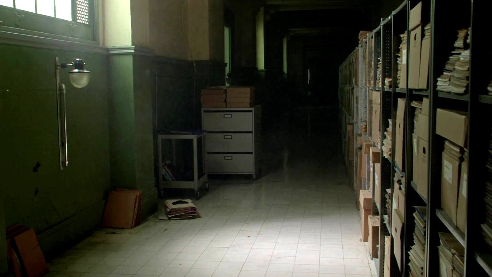 Couloir administratif bordé d'étagères d'archives et de cartons de dossiers