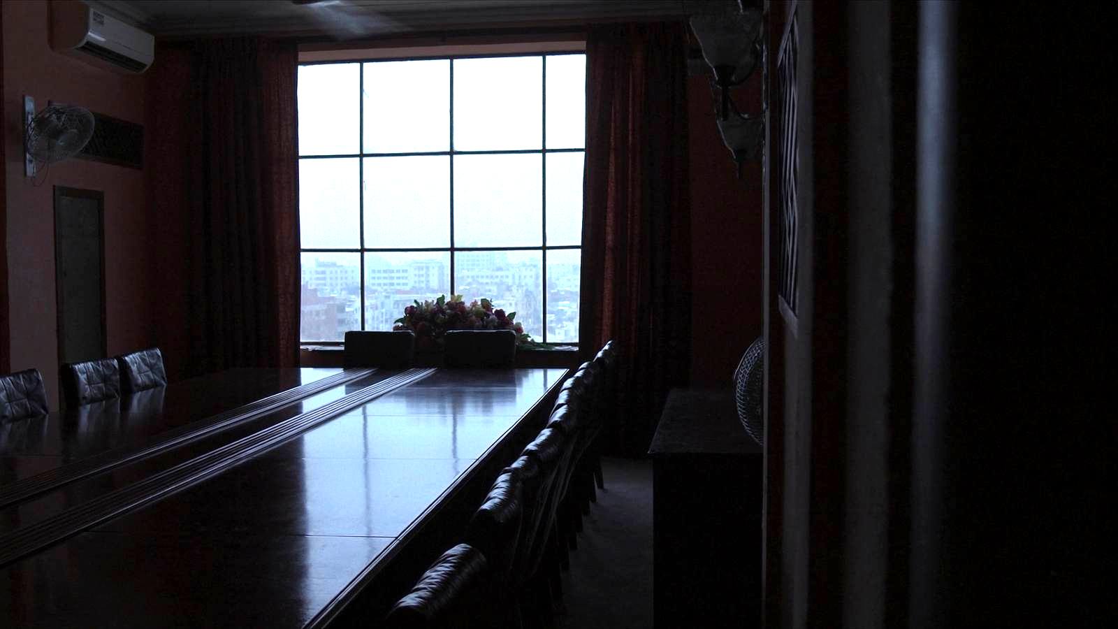 Salle de réunion vide, table longue, lumière du matin sur une ville sahélienne
