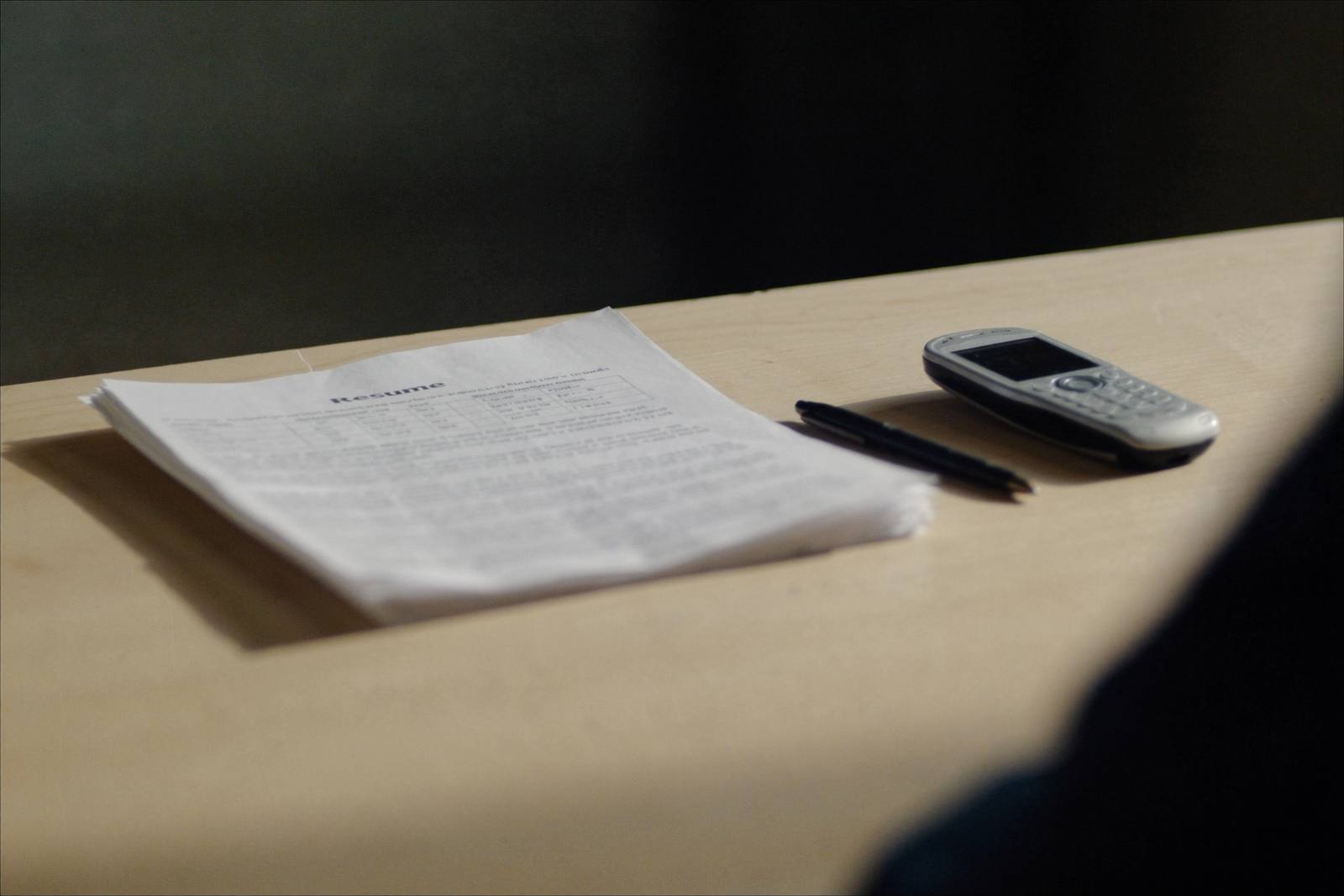 Bureau simple avec une pile de curriculum vitae imprimés, un stylo et un téléphone